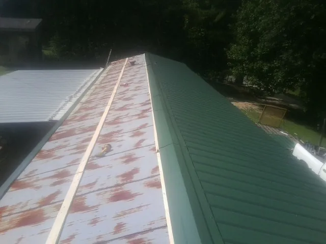 Old rusted panels beside newly installed green metal roofing — Wind Damage Roof Repair by Roofing Brothers in Davenport